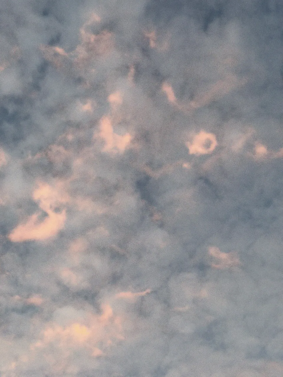 Ein wolkenverhangener Himmel in sanften Rosa- und Blautönen während der Dämmerung.
